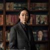 电影研究学者林晓影，日本电影史专家，身着深色西装，背景为书架与电影海报